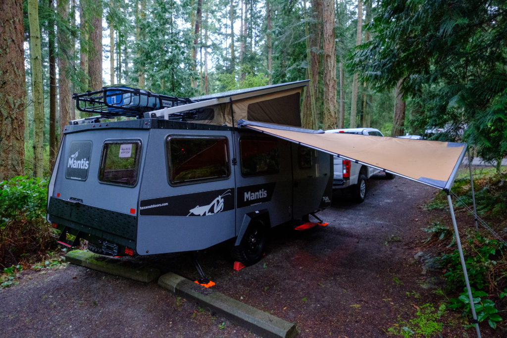 Mantis in a forested campsite on a rainy day with the awning setup